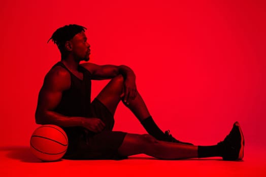 Becoming a skilled player takes a lot of exercise and dedication. Red filtered shot of a young sportsman posing with a basketball in the studio.