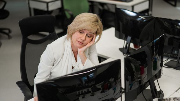 Caucasian blonde woman sleeping at her desk in the office.