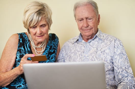 Maintaining their financial freedom with modern technology. a senior couple making a credit card payment on a laptop together at home.