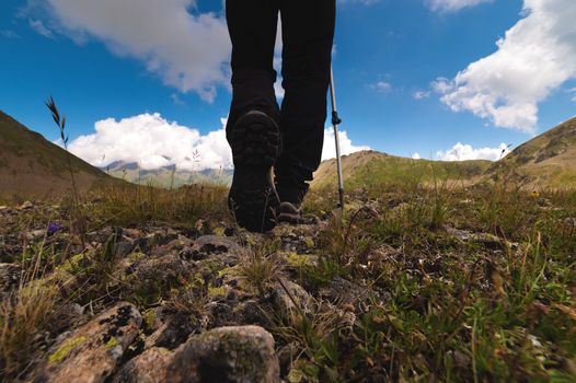 Close-up of boots while hiking on a trail in the mountains. Man walking in sports shoes overlooking nature from the ground