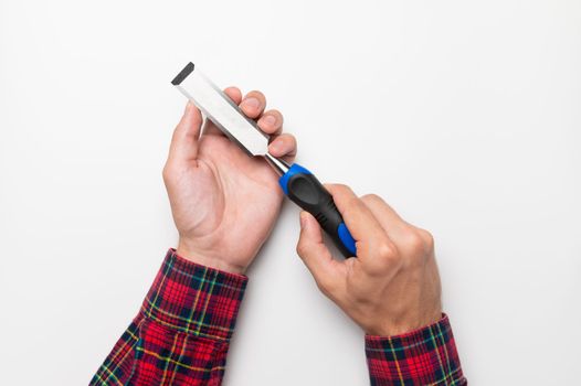 Hand tool chisel on a white background in a man's hand, top view. Craftsman in a plaid shirt holds a carpentry hand cutting tool