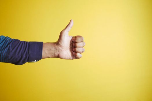 man hand showing a thumb-up on yellow background