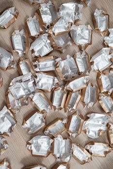 Pile of empty silver-gold candy wrappers. Top view.