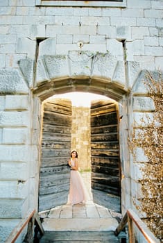 Bride opens the shabby old wooden door of the stone fortress