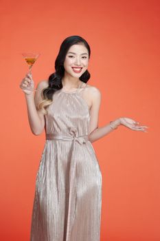 Beautiful young lady in glitter evening dress with wine glass in hand