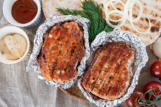Grilled pork meat in foil with flapjack and vegetables