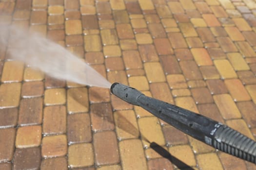 Cleaning backyard paving tiles with high pressure washer. Spring clean up. Cleaning dirty backyard paving tiles with pressure washer cleaner