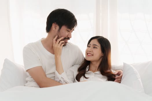 Asian couple lying in bed in a home, anniversary or romance. Intimacy, happy while on romantic vacation, trip