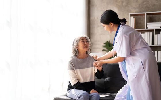 Young caregiver helping senior woman walking. Nurse assisting her old woman patient at nursing home. Senior woman with walking stick being helped by nurse at home