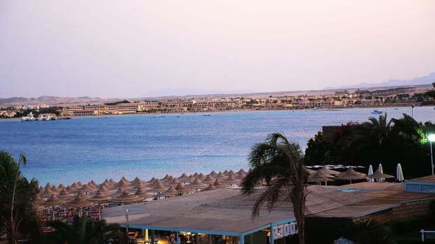 Egyptian resort. One of many quiet coves of the Red Sea, at sunset, at dusk. against the background of the outlines of buildings, palm trees, mountains .