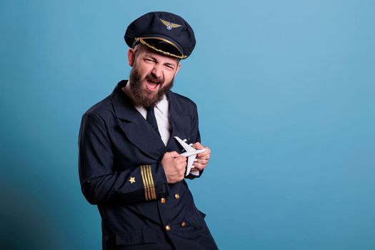 Funny pilot in uniform playing with small airplane model