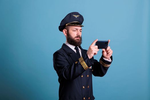 Plane pilot in uniform watching online video on smartphone