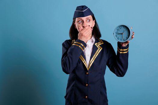 Anxious stewardess holding retro alarm clock