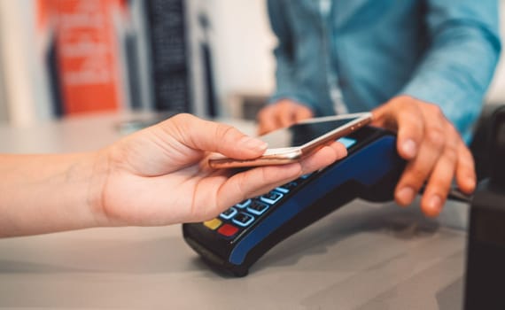 Wireless payment with a phone - Person holding a phone over the credit card reader