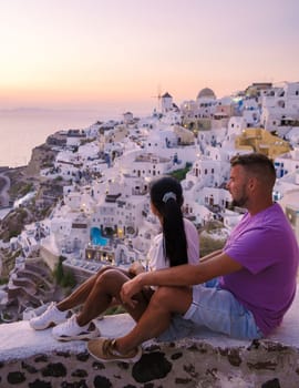 Couple watching sunset on vacation Santorini Greece, men and women visit the Greek village of Oia