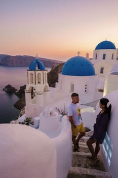 Men and women visit the whitewashed Greek village of Oia Santorini, couple watch sunrise Santorini