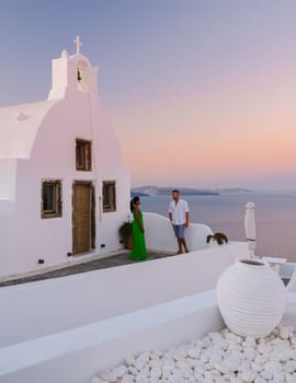 Couple watching sunset on vacation in Santorini Greece, men and women watching the village Oia