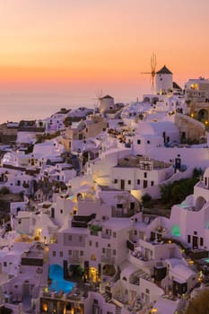 Sunset with white churches an blue domes by the ocean of Oia Santorini Greece