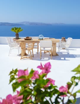 outside terrace of a restaurant by the ocean of Santorini Greece, chairs and tabel with flowers by the ocean