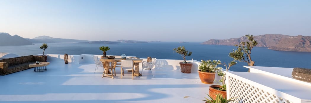 outside terrace of a restaurant by the ocean of Santorini Greece, chairs and tabel with flowers by the ocean