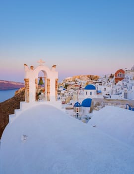 Sunset with white churches an blue domes by the ocean of Oia Santorini Greece