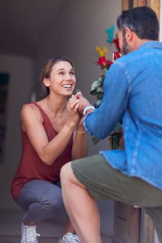 He finally popped the question. an attractive young woman accepting a marriage proposal on her doorway at home.