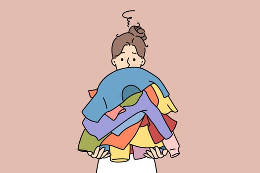 Unhappy woman holding pile of dirty clothes