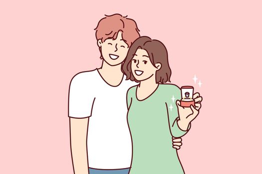 Young couple of man and woman stand in embrace showing box with wedding ring. Vector image