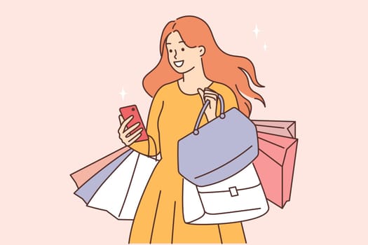 Smiling woman with shopping bags and cellphone