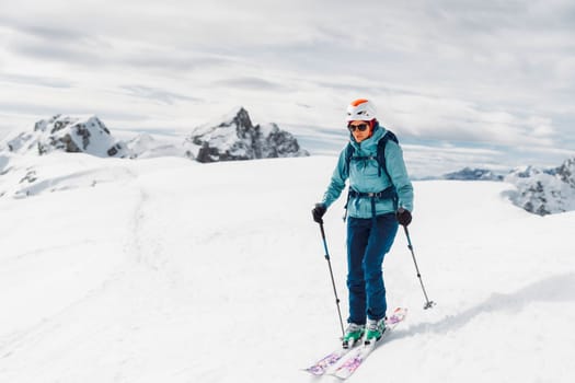 Portrait of a ski tourer in blue ski jacket and white helmet, ready to ski down the mountain