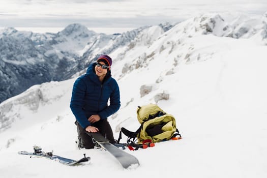 Smiling ski tourer getting his ski ready to ski down the snowy mountain