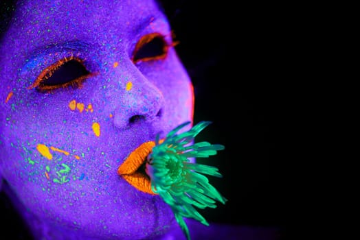 Weird and wonderful. a young woman posing with neon paint on her face.