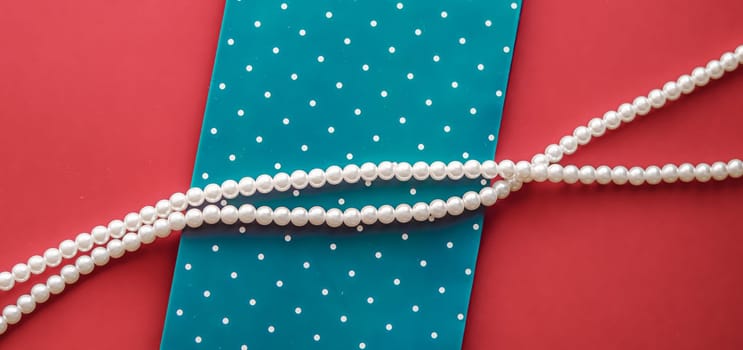 Pearl jewellery necklace and abstract blue polka dot background on coral backdrop