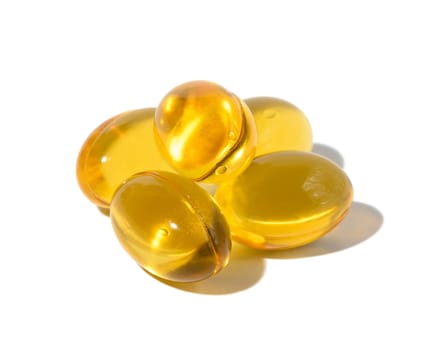 Yellow capsules with fish oil on a white background, close up