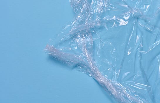 Crumpled transparent polyethylene on a blue background, top view