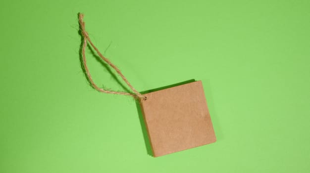 Brown paper square paper tag with rope on green background