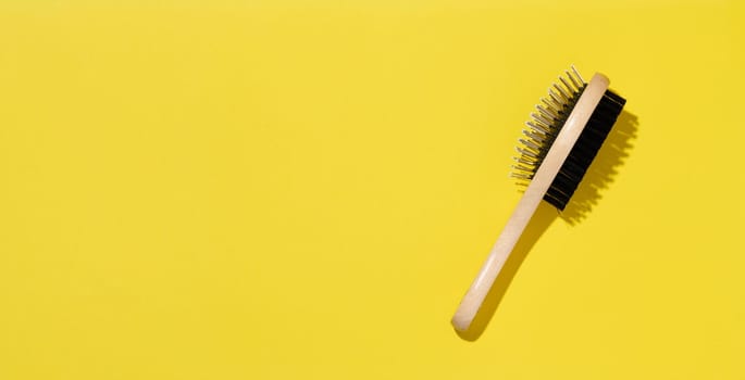 Wooden animal brush on yellow background, top view