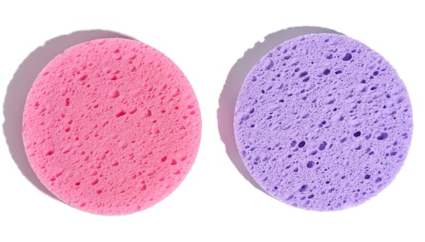 Round purple and pink makeup sponges on a white isolated background