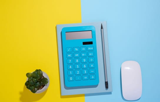 Blue notepad, calculator and wooden pencil on a blue background