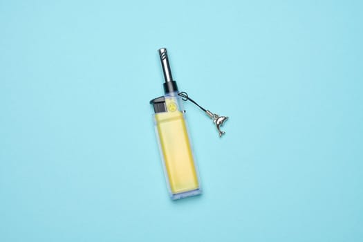 Yellow plastic lighter on a blue background, top view