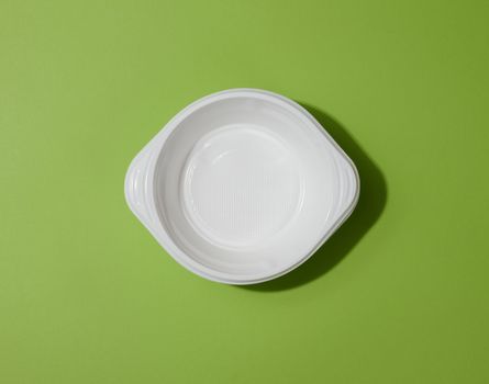 White empty plastic soup bowl on green background, top view