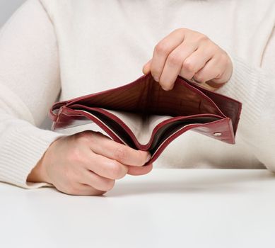 Two female hands hold an empty brown leather wallet, poverty
