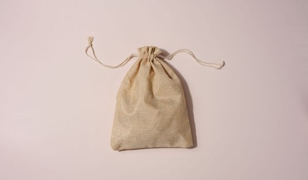 Beige full canvas bag on a beige background, top view