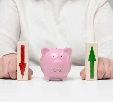 Pink ceramic piggy bank and wooden blocks with up arrow. Concept of increasing interest on a deposit in a bank, high return on investment, large margin on sale