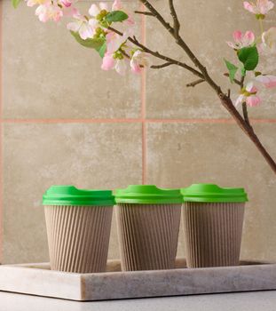 Paper brown cups with a plastic green lid for coffee and tea