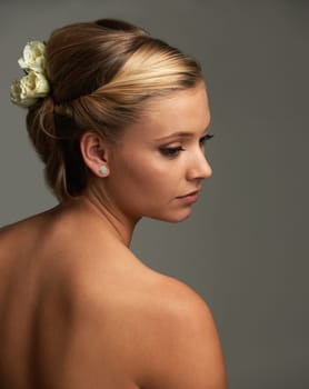 Elegance and natural beauty. Rearview studio shot of an attractive young woman with a flower in her hair.