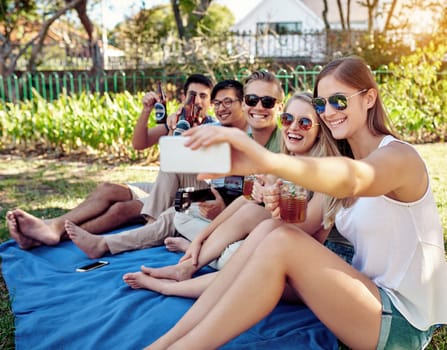 Lemme get one with all of us. a young group of friends taking selfies while enjoying a few drinks outside in the summer sun.