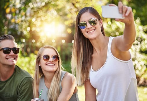 Smile. a young group of friends taking selfies while enjoying a few drinks outside in the summer sun.