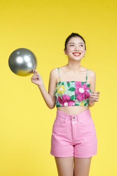 Charming lady holding hand air balloon decorations for birthday party  isolated yellow color background