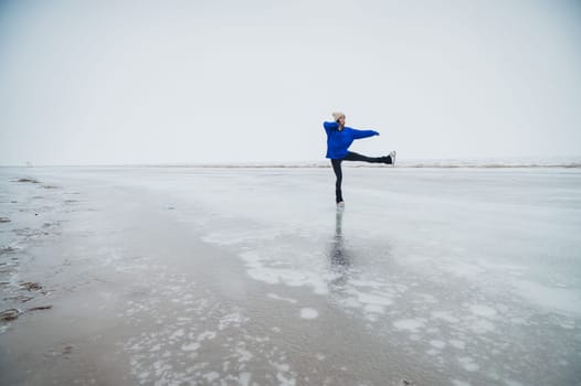 Caucasian woman in a blue sweater skating on a frozen lake.
